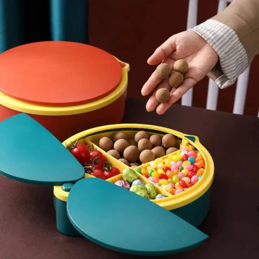 Organizador de 4 compartimentos, amarillo y verde, con tapas y varios dulces, tomates y frutos secos.