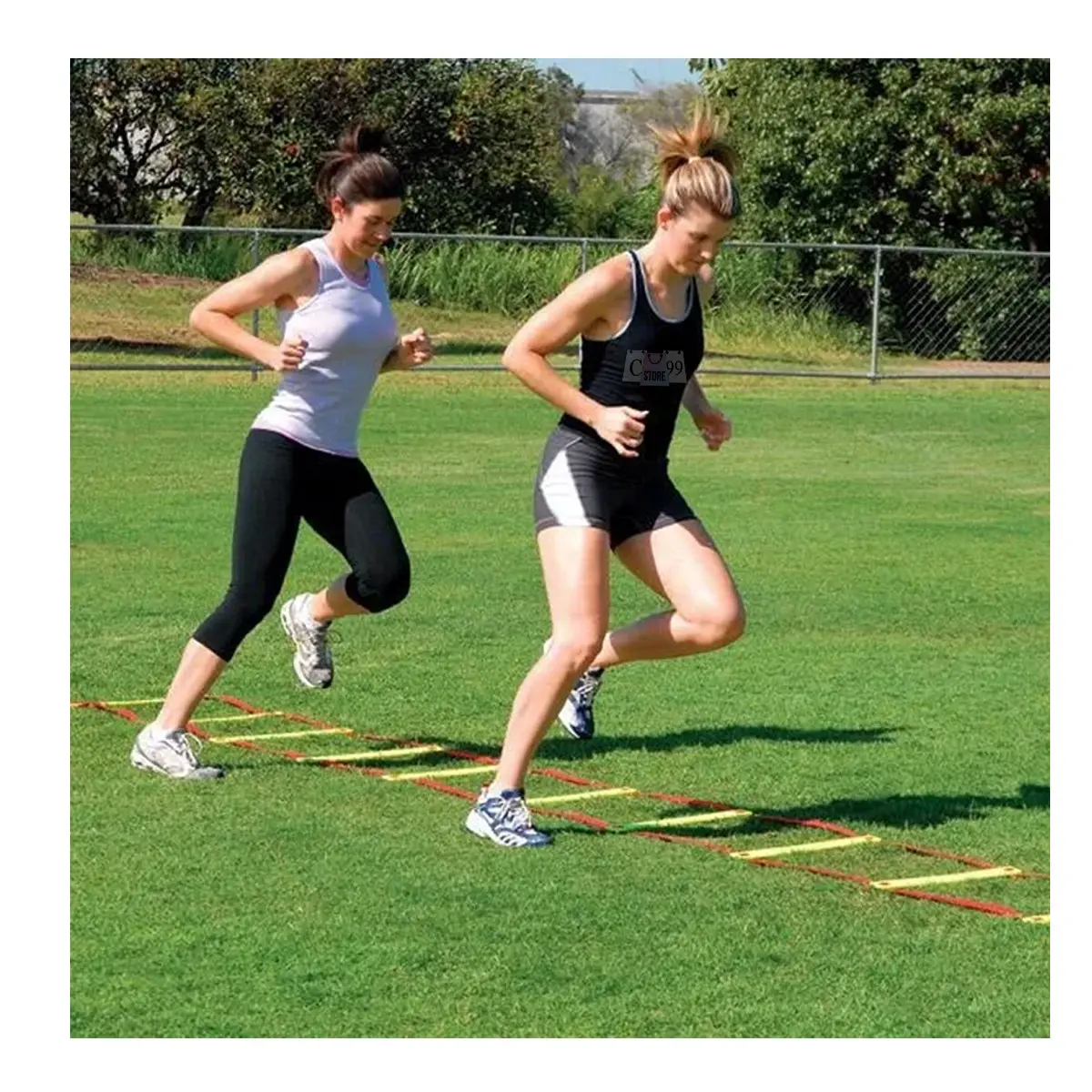 Dos mujeres entrenan agilidad en césped con escalera deportiva, una con camiseta blanca y leggins negros, otra con top negro y shorts.