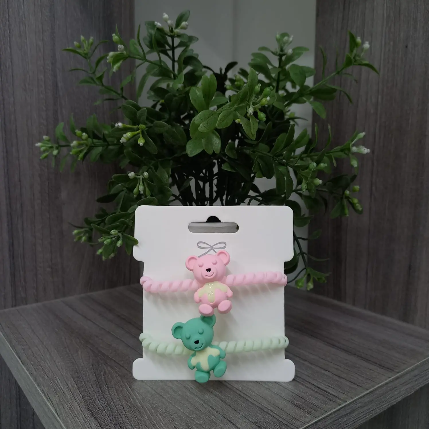 Moñitas espiral para cabello con dijes de ositos en rosa y verde, presentadas en empaque blanco.
