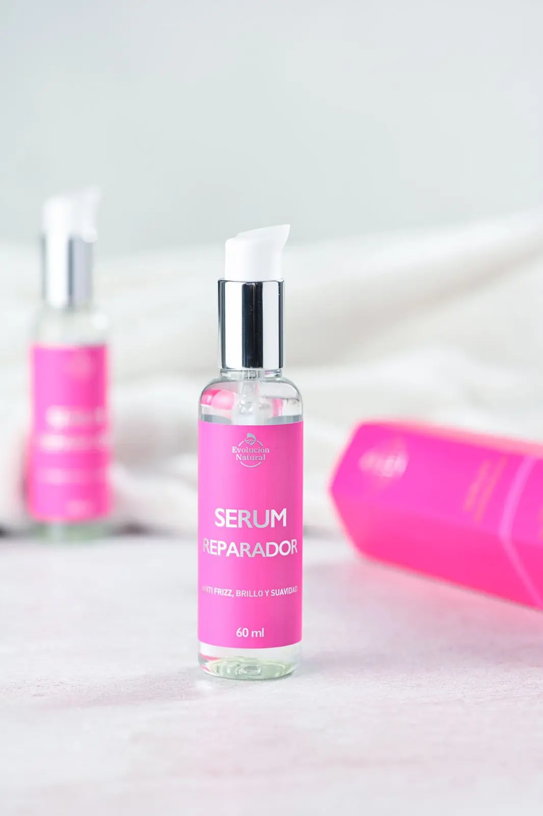 Serum reparador Evolución Natural 60 ml en frasco transparente con etiqueta rosa, ideal para controlar frizz y sellar puntas.