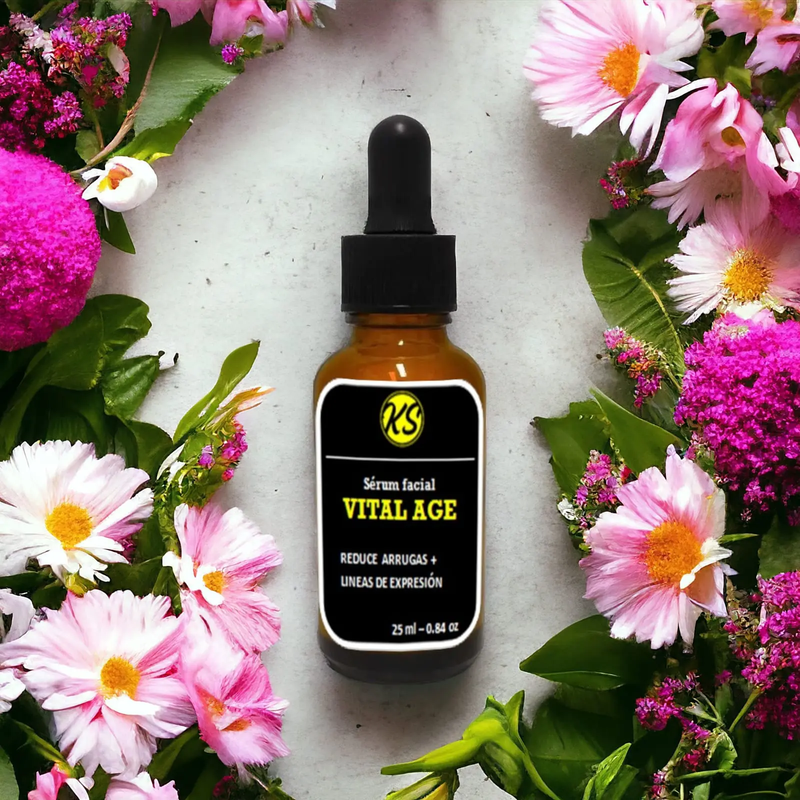Serum facial Vital Age en frasco ámbar con gotero, rodeado de flores rosadas y fucsias.
