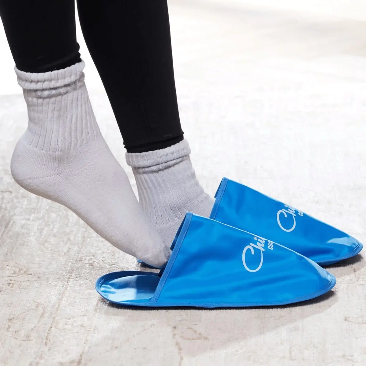 Pantuflas azules para terapia de frío y calor, usadas sobre calcetines blancos.