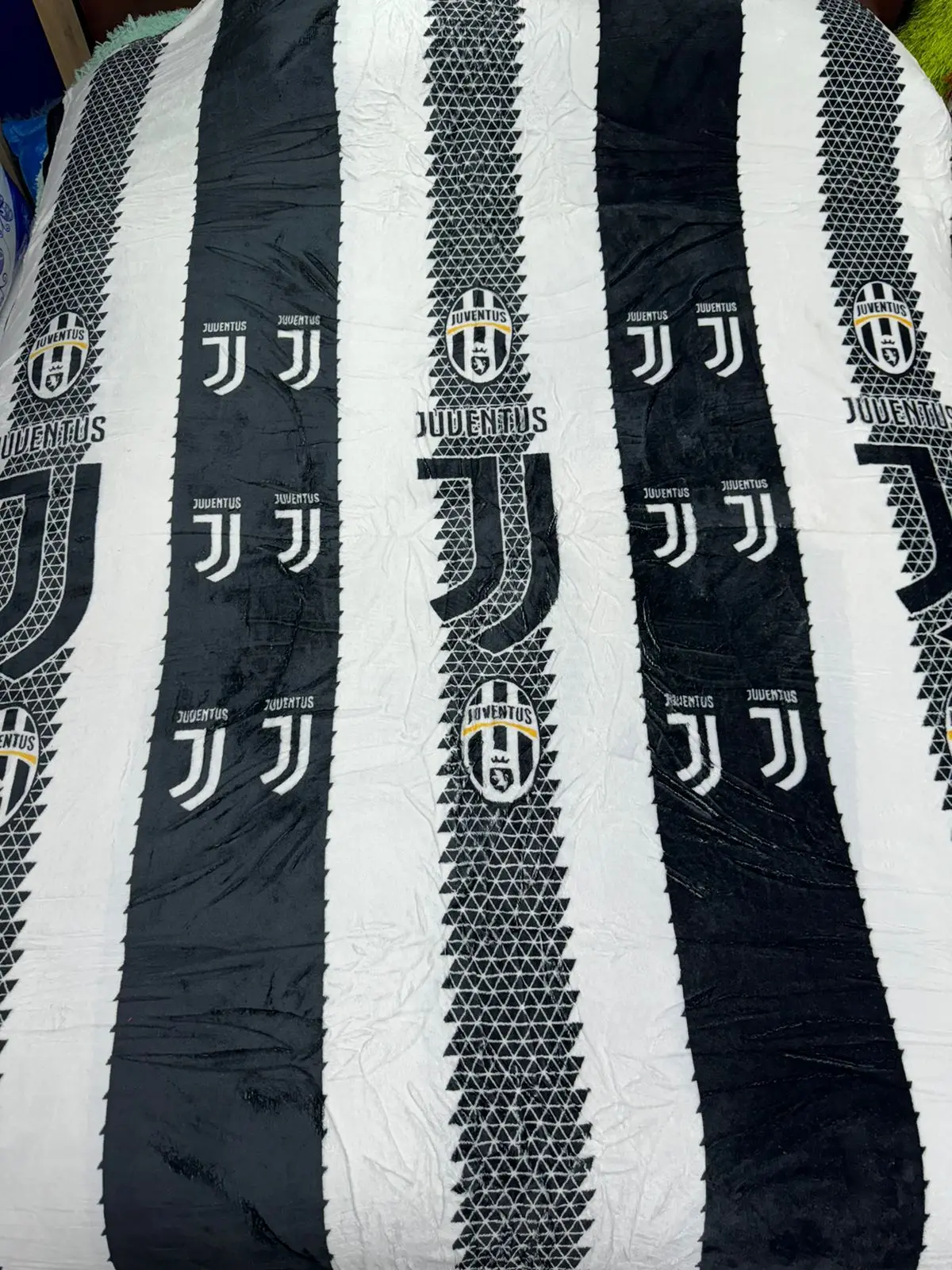 Cobija deportiva Juventus con franjas blancas y negras, diseño con escudo y logo repetidos.