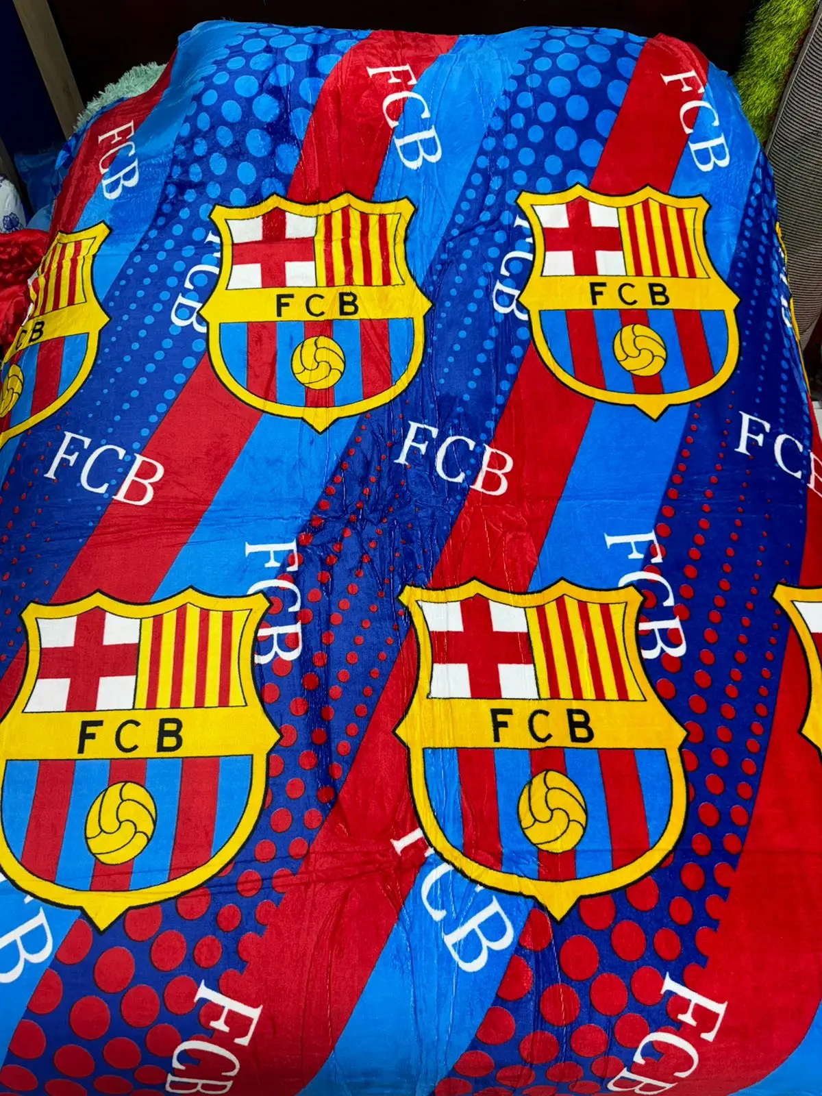 Cobija deportiva FCB azul y roja con logo repetido, textura suave.