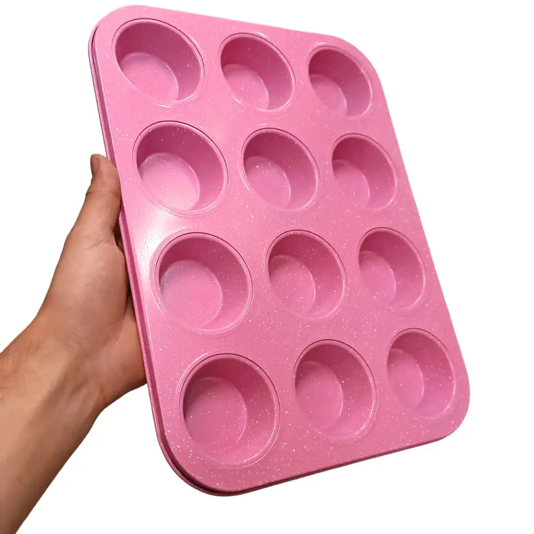 Molde para 12 muffins antiadherente rosa con textura moteada, sujetado por una mano.