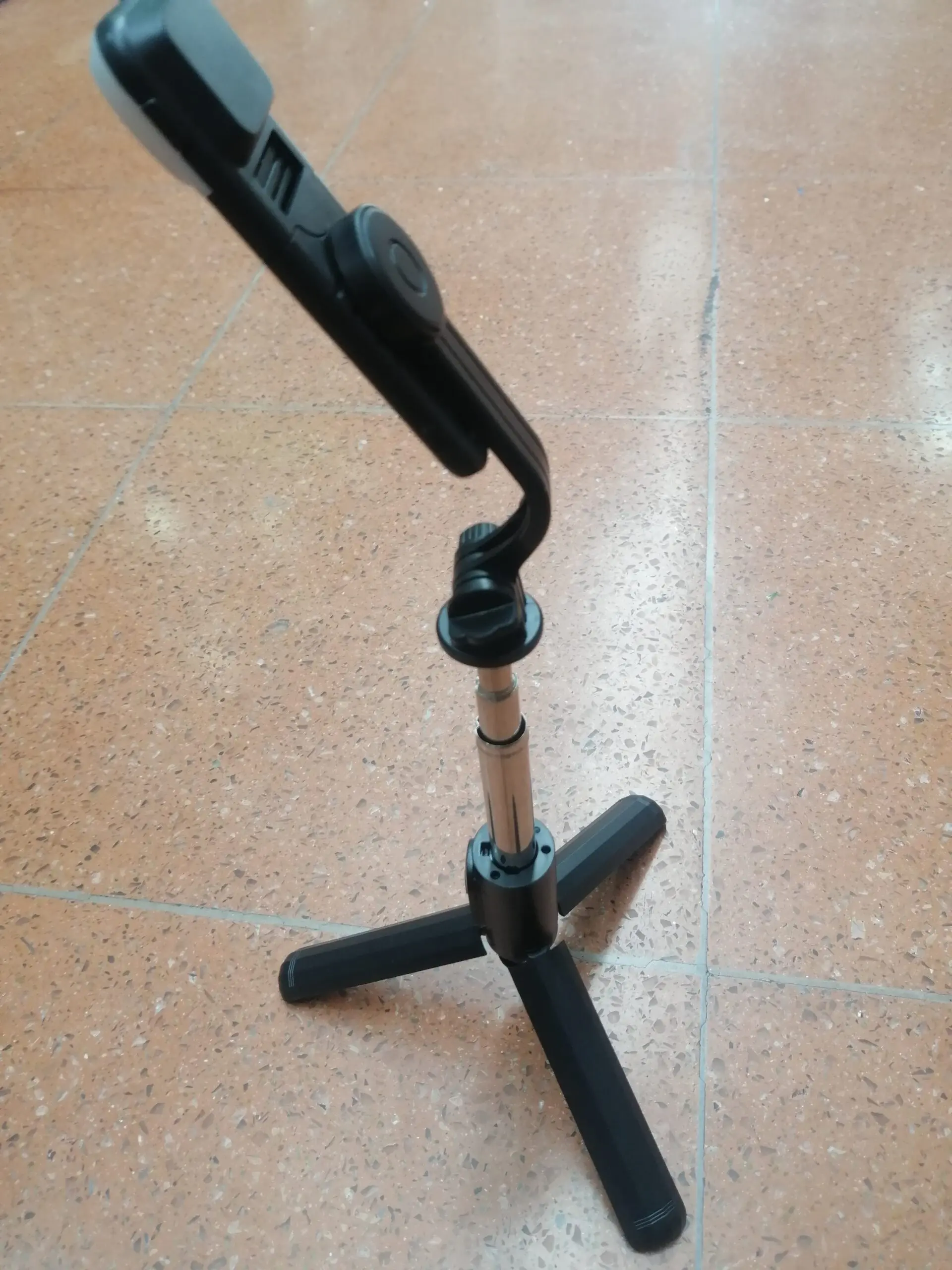 Trípode negro para celular con base plegable y conector ajustable, ideal para grabaciones y fotos estables.