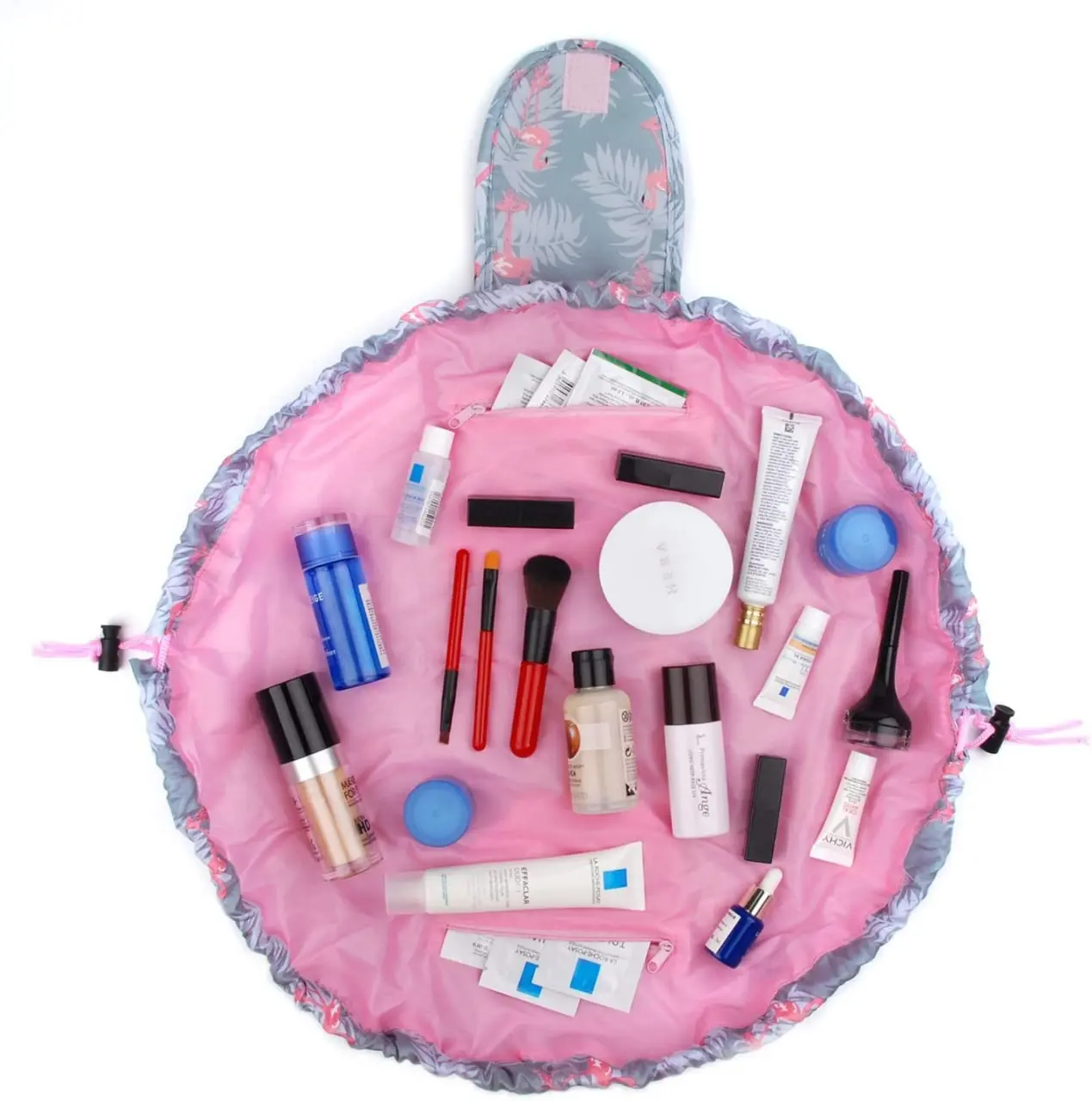 Organizador de maquillaje abierto, color rosa con estampado de flamencos, lleno de productos de belleza y brochas.