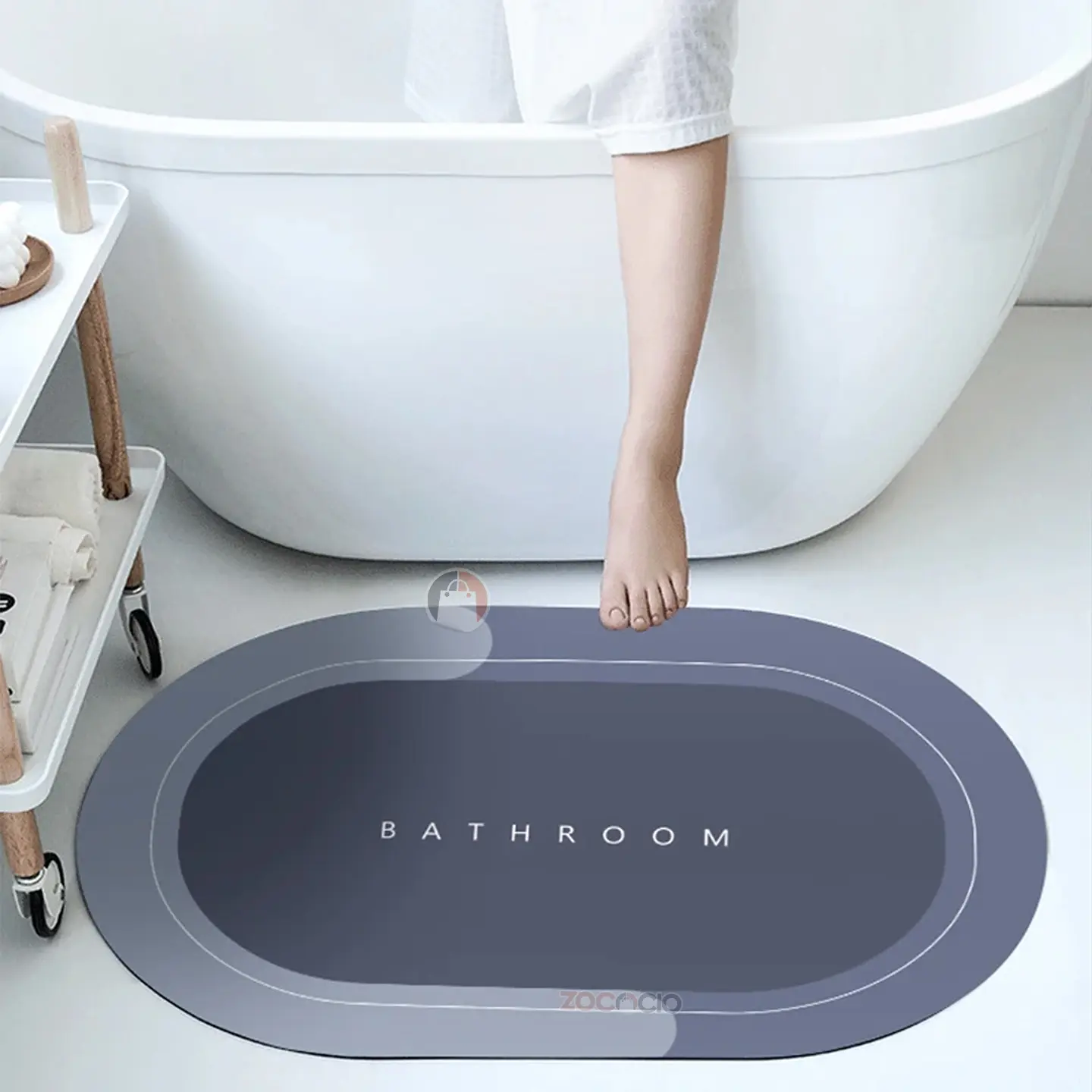 Alfombra de baño ovalada gris oscuro, suave y absorbente, con texto "BATHROOM" y logo ZOCACIO.