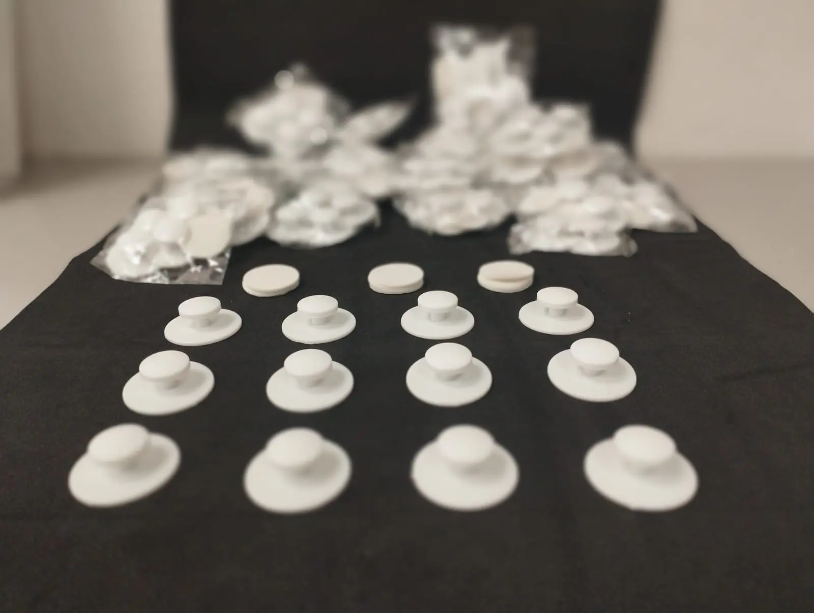 Docena de ganchos adhesivos blancos para colgar con base circular y botón.
