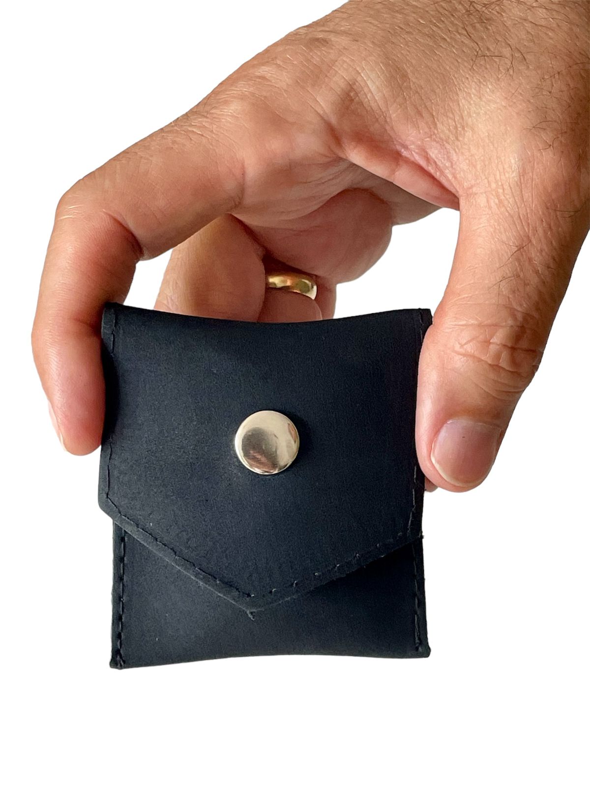 Mano sostiene portaaccesorios de cuero negro con broche metálico.