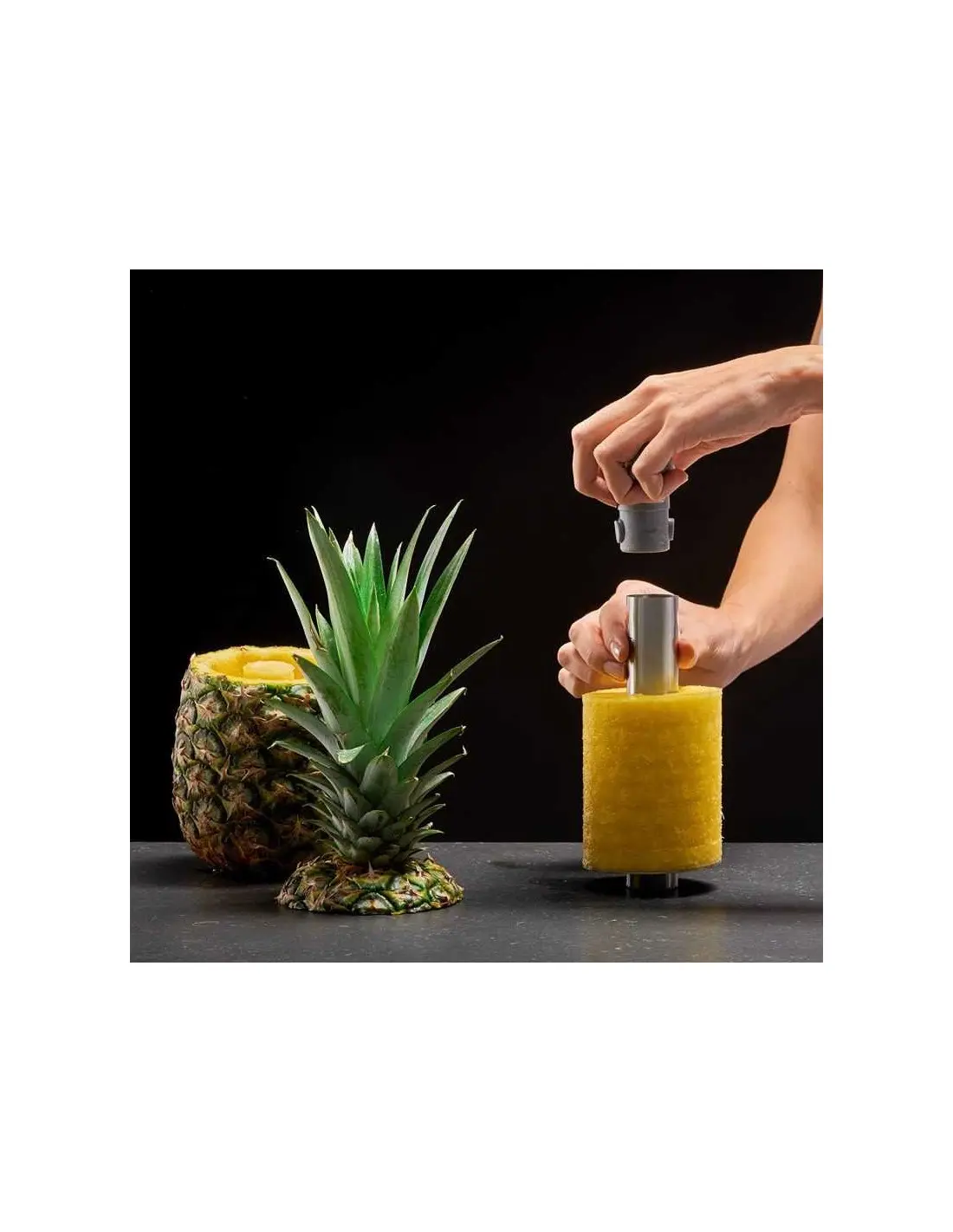 Pelador de piña en acción: manos extraen espiral de fruta amarilla lista para servir.