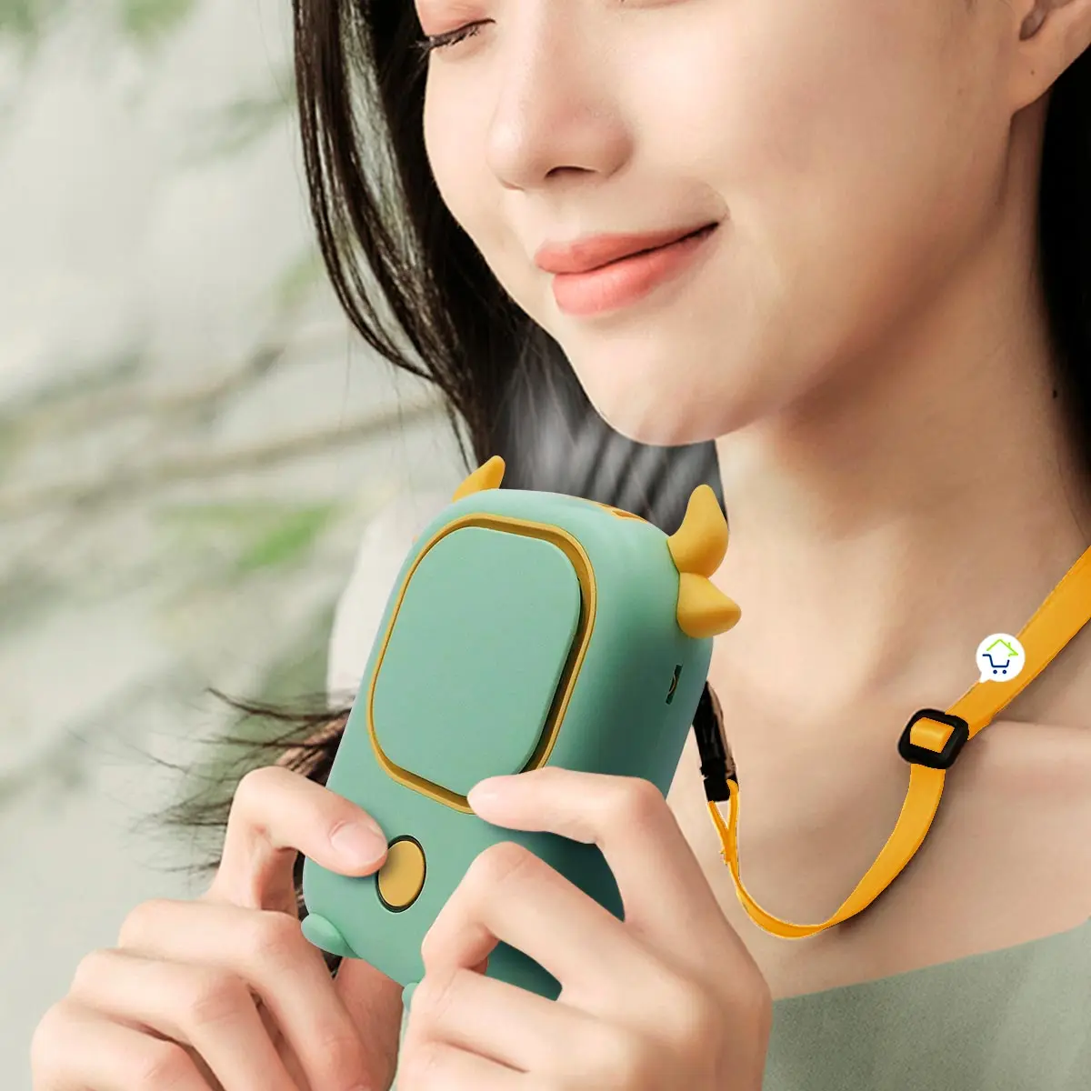 Ventilador de cuello portátil en forma de vaca, color verde menta con detalles dorados, sostenido por una mujer.