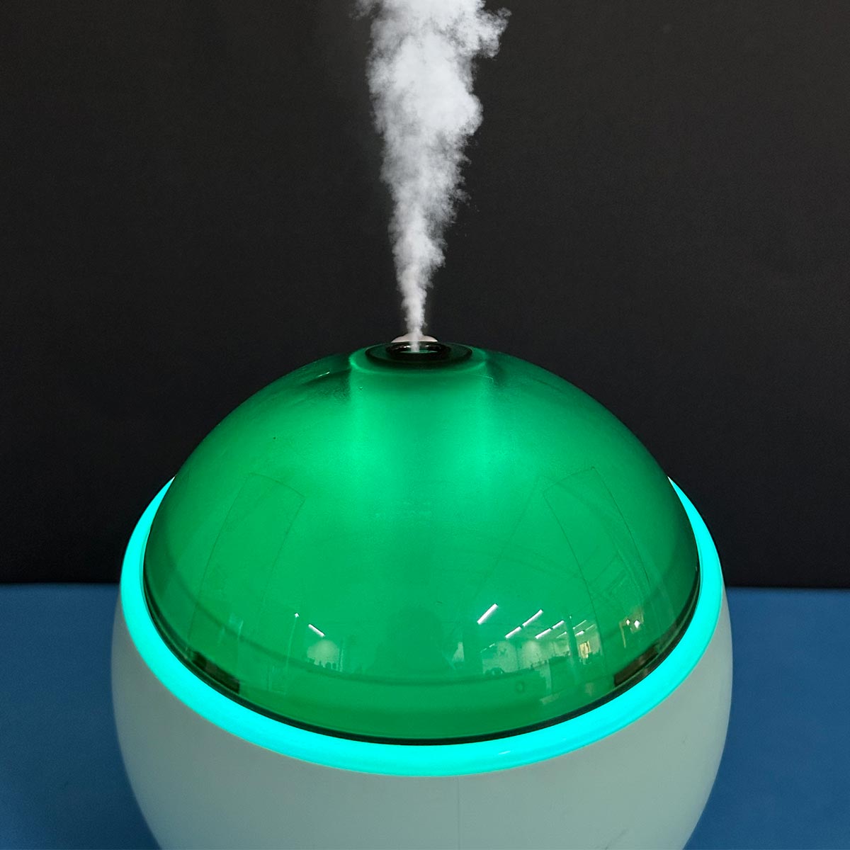 Humidificador Q803 blanco con cúpula verde translúcida y luz led azul emitiendo vapor.
