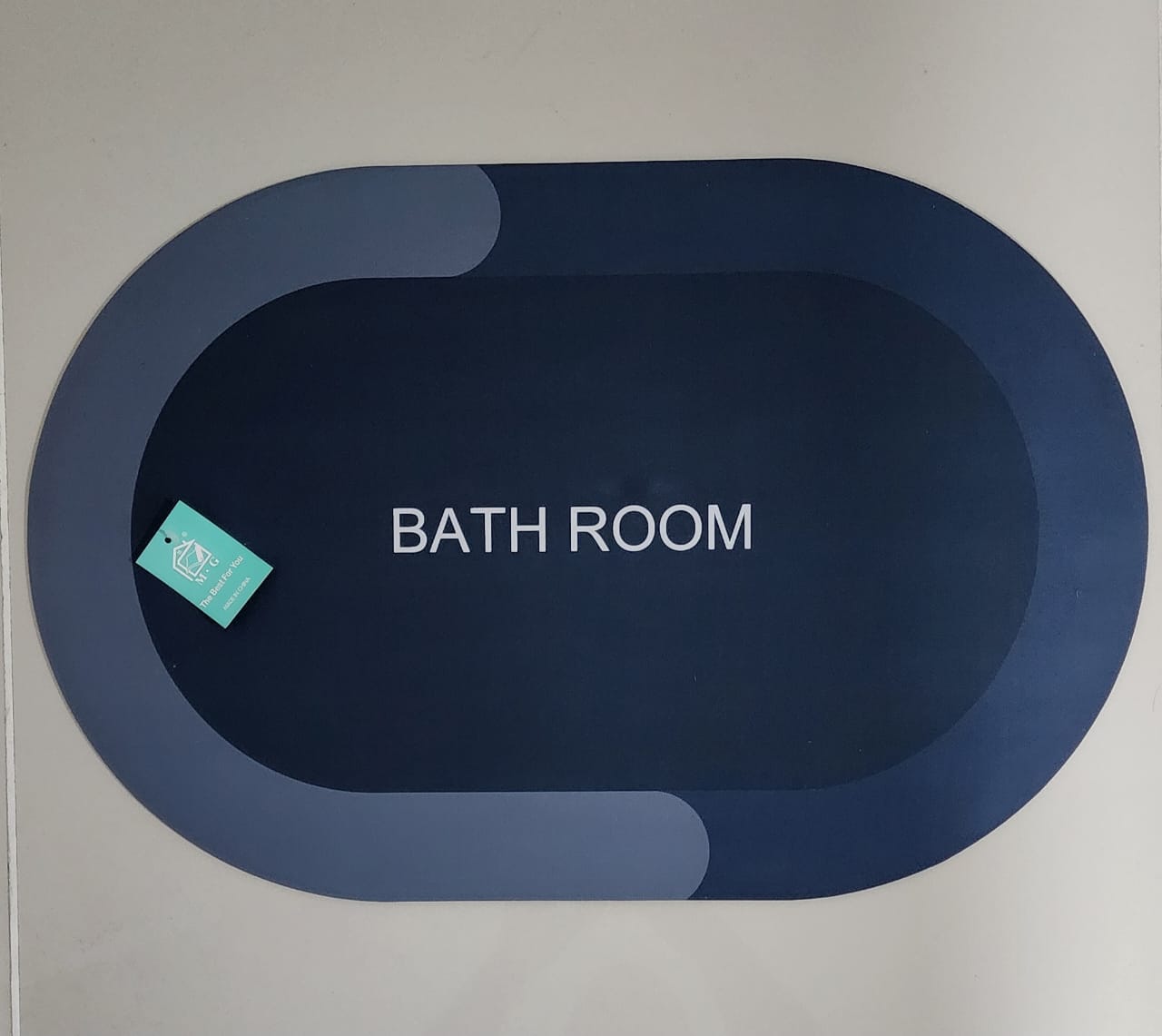 Tapete antideslizante ovalado azul oscuro para baño, con diseño moderno y etiqueta.