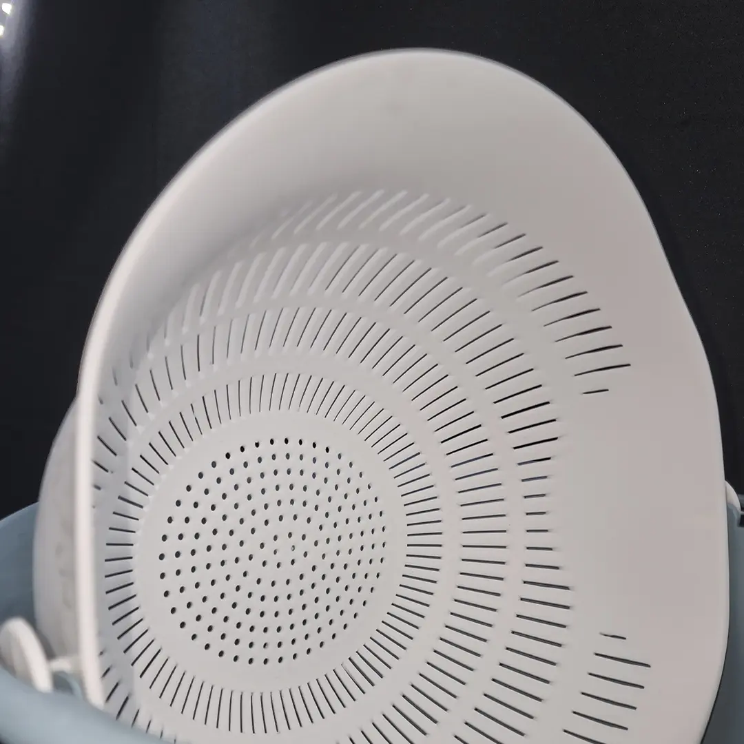 Colador blanco de plástico con múltiples orificios y escurridor giratorio incorporado, apto para lavar frutas y verduras.