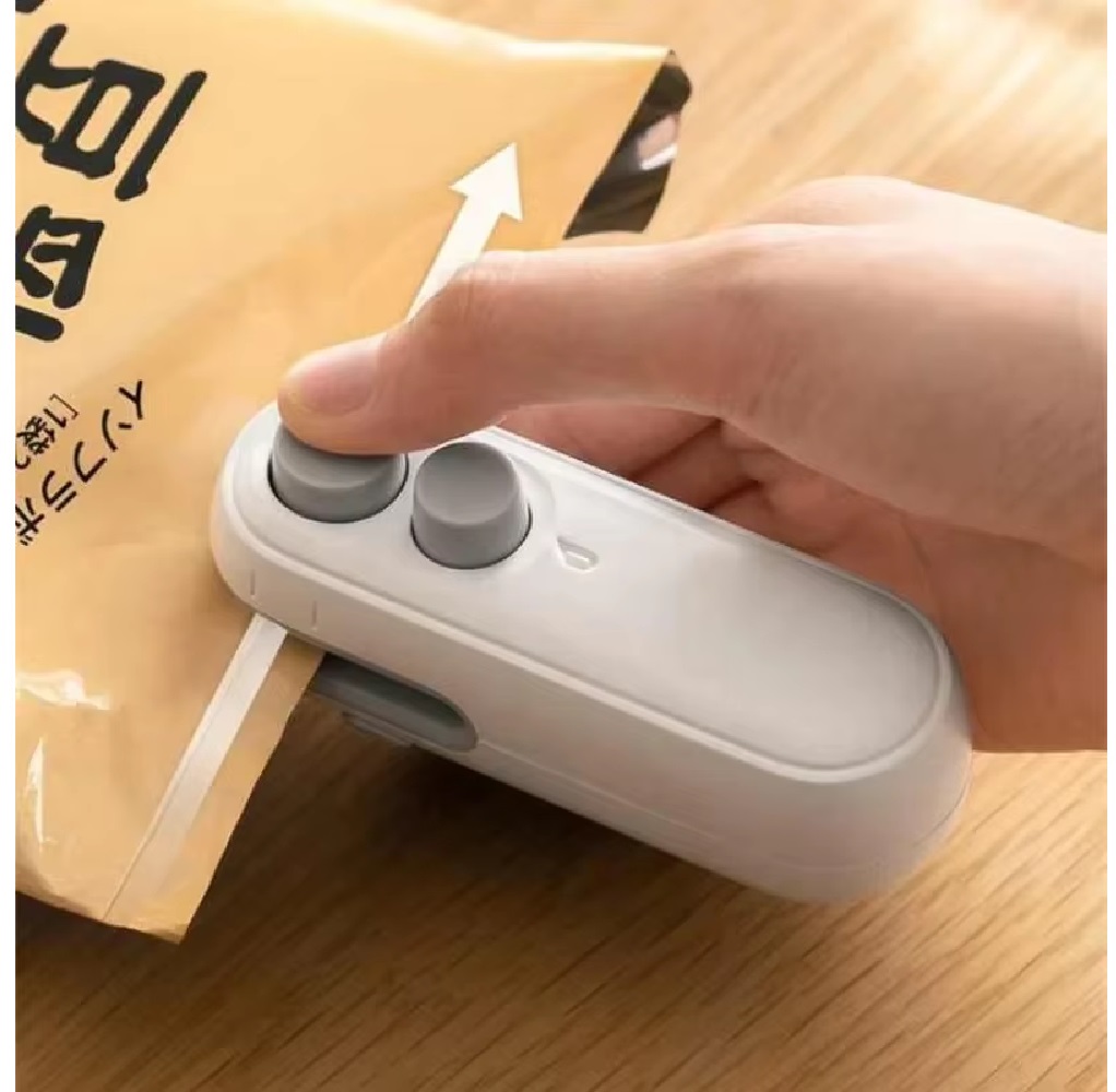 Mini sellador de bolsas blanco 2 en 1 en uso, sellando paquete marrón.