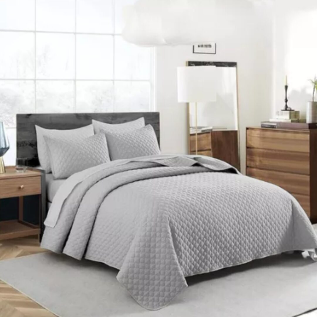 Colcha española doble faz gris con textura acolchada en cama matrimonial, con almohadas a juego.