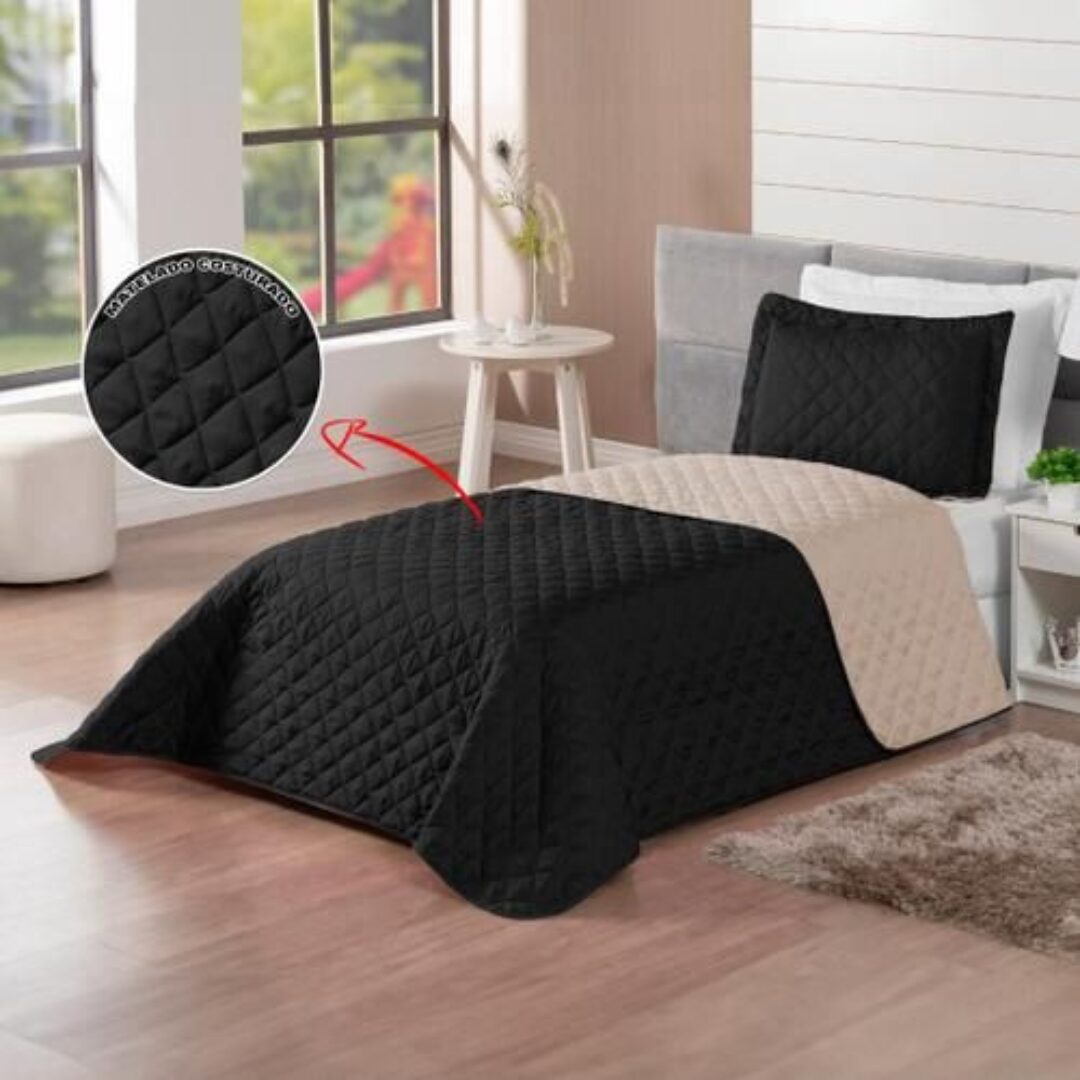 Colcha española doble faz negra y beige, acolchada con diseño rombos, sobre cama.
