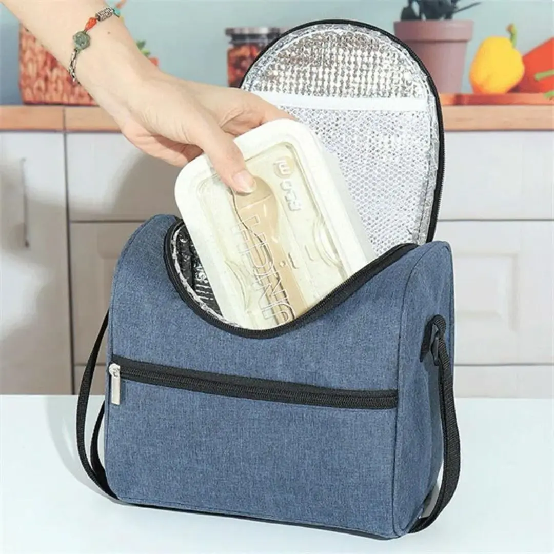 Lonchera térmica azul con interior plateado, mano guardando recipiente para almuerzo.