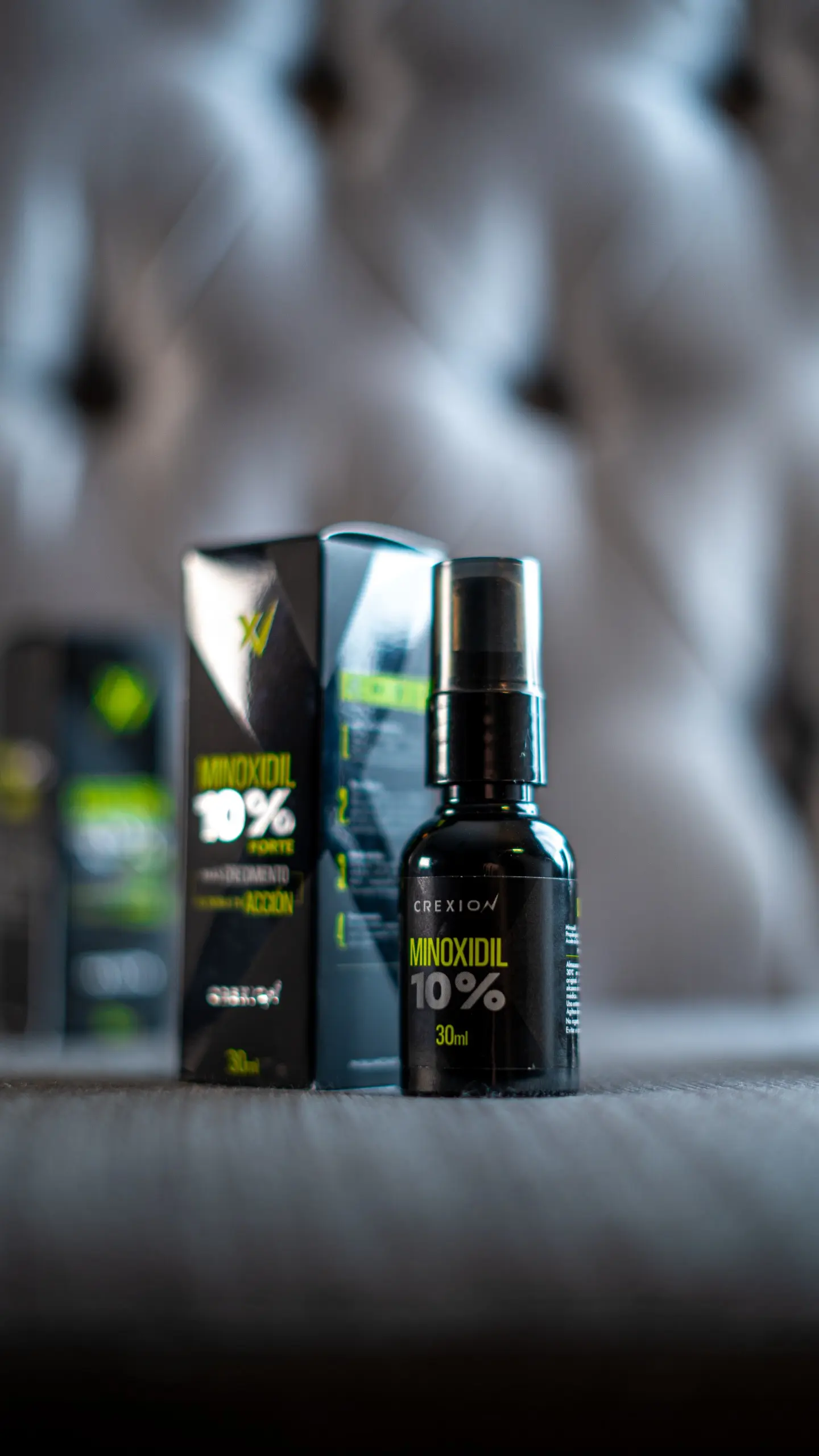 Set x2 Minoxidil 10% Crexion, frasco spray negro sobre fondo texturizado gris.