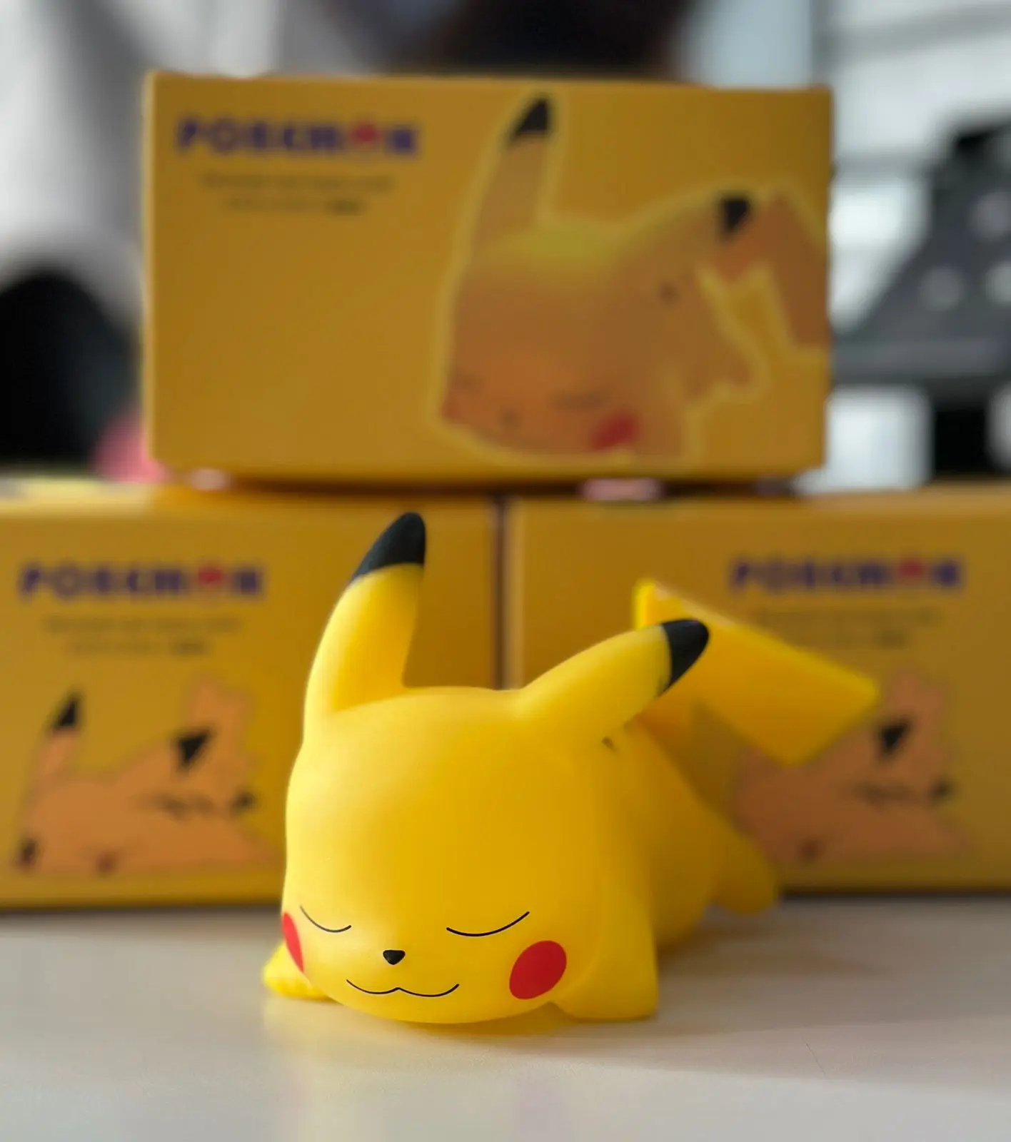 Pikachu durmiendo en miniatura, con caja Pokémon al fondo, luz LED, diseño infantil.