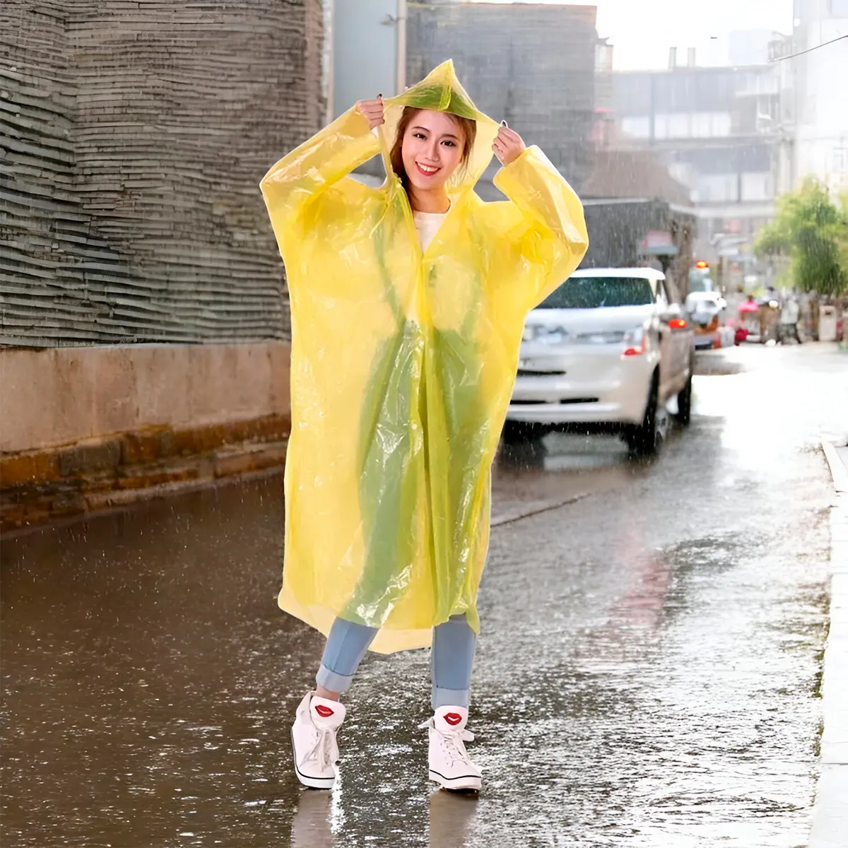Mujer joven con impermeable amarillo brillante y capucha, parada en calle lluviosa y mojada.