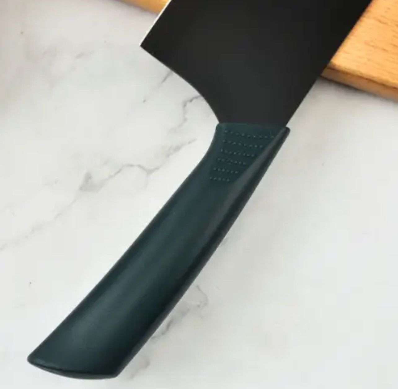 Cuchillo de cocina negro con mango ergonómico verde oscuro texturizado, perfil de corte amplio.