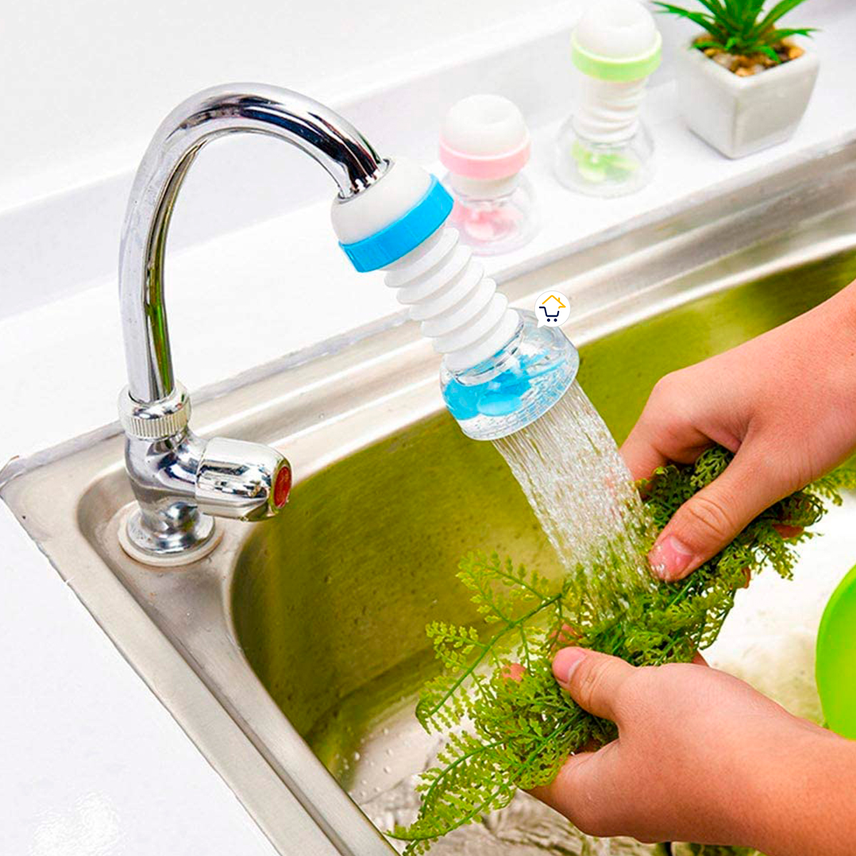 Ahorrador de agua flexible azul y blanco para grifo, lavando ramas verdes en fregadero de acero inoxidable.