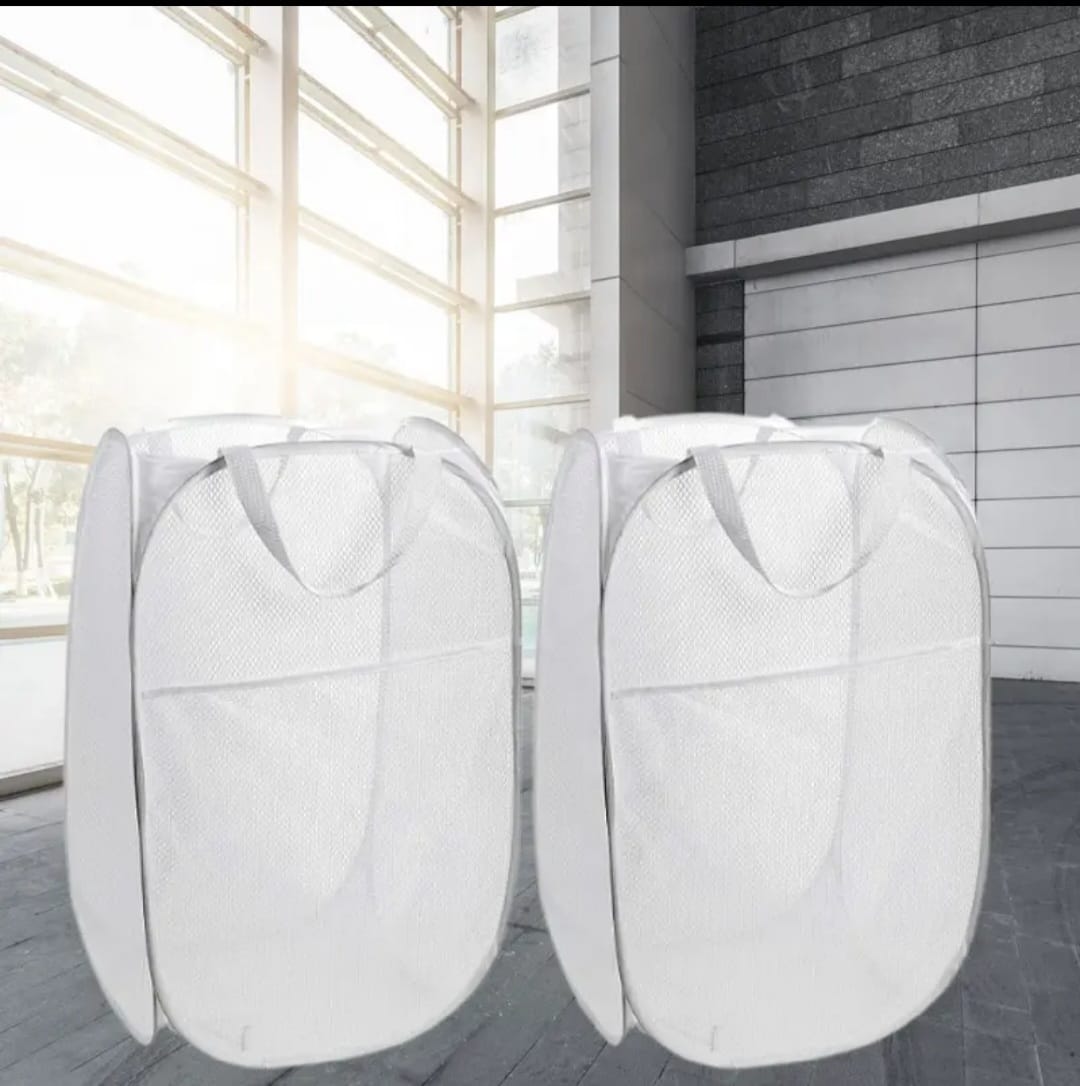 Dos canastas de ropa blancas plegables de malla, con asas, en interior moderno.