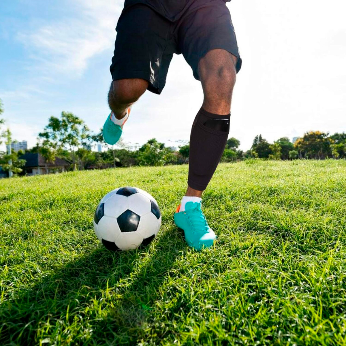 Media deportiva negra 25cm para futbolista pateando balón en césped.