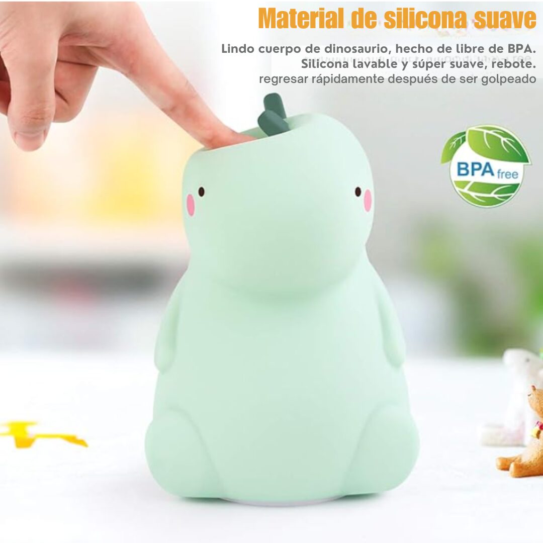 Lámpara nocturna de silicona suave color verde menta con forma de dinosaurio, siendo presionada por un dedo para demostrar su textura flexible y lavable.