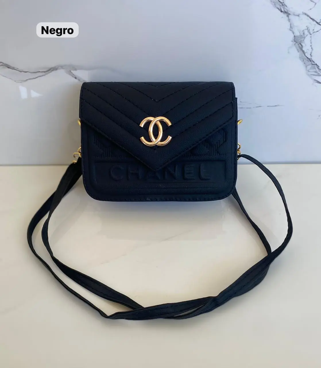 Bolso negro Mani Cartera Chanel con logo dorado y correa cruzada.