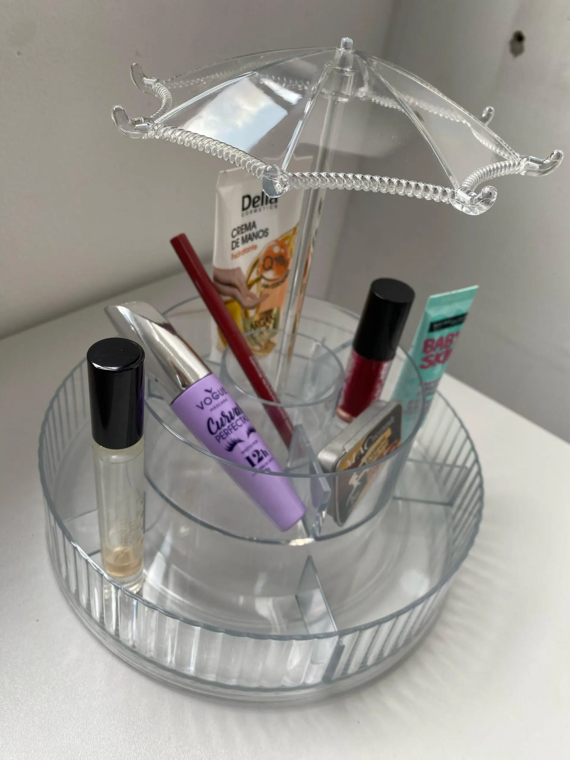 Organizador giratorio de maquillaje transparente con cosméticos como máscara, labial y crema de manos.