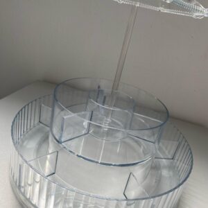Organizador de maquillaje acrílico transparente con forma de sombrilla, niveles giratorios y compartimentos.