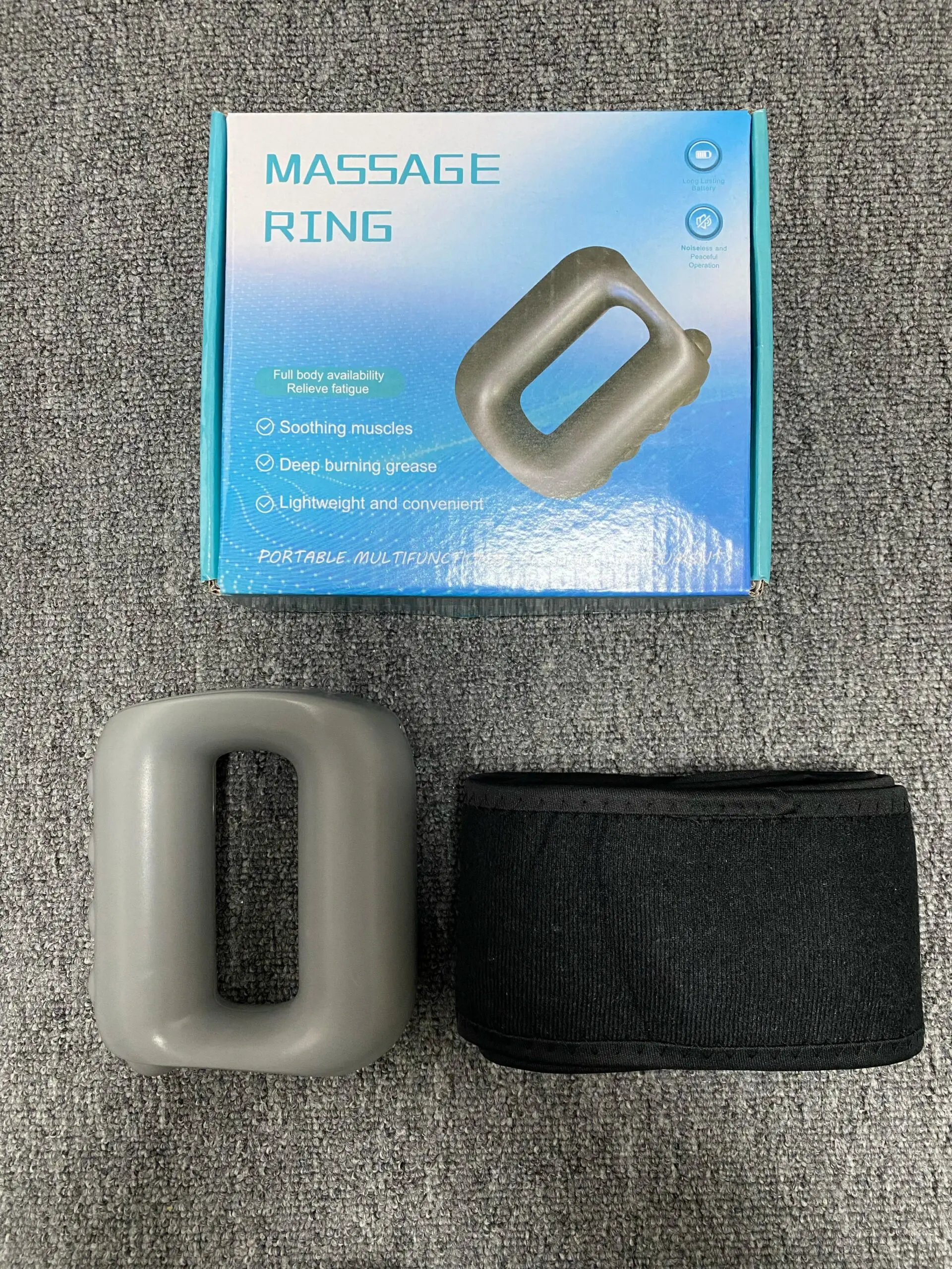 Anillo masajeador corporal gris y cinturón negro sobre fondo gris texturizado.