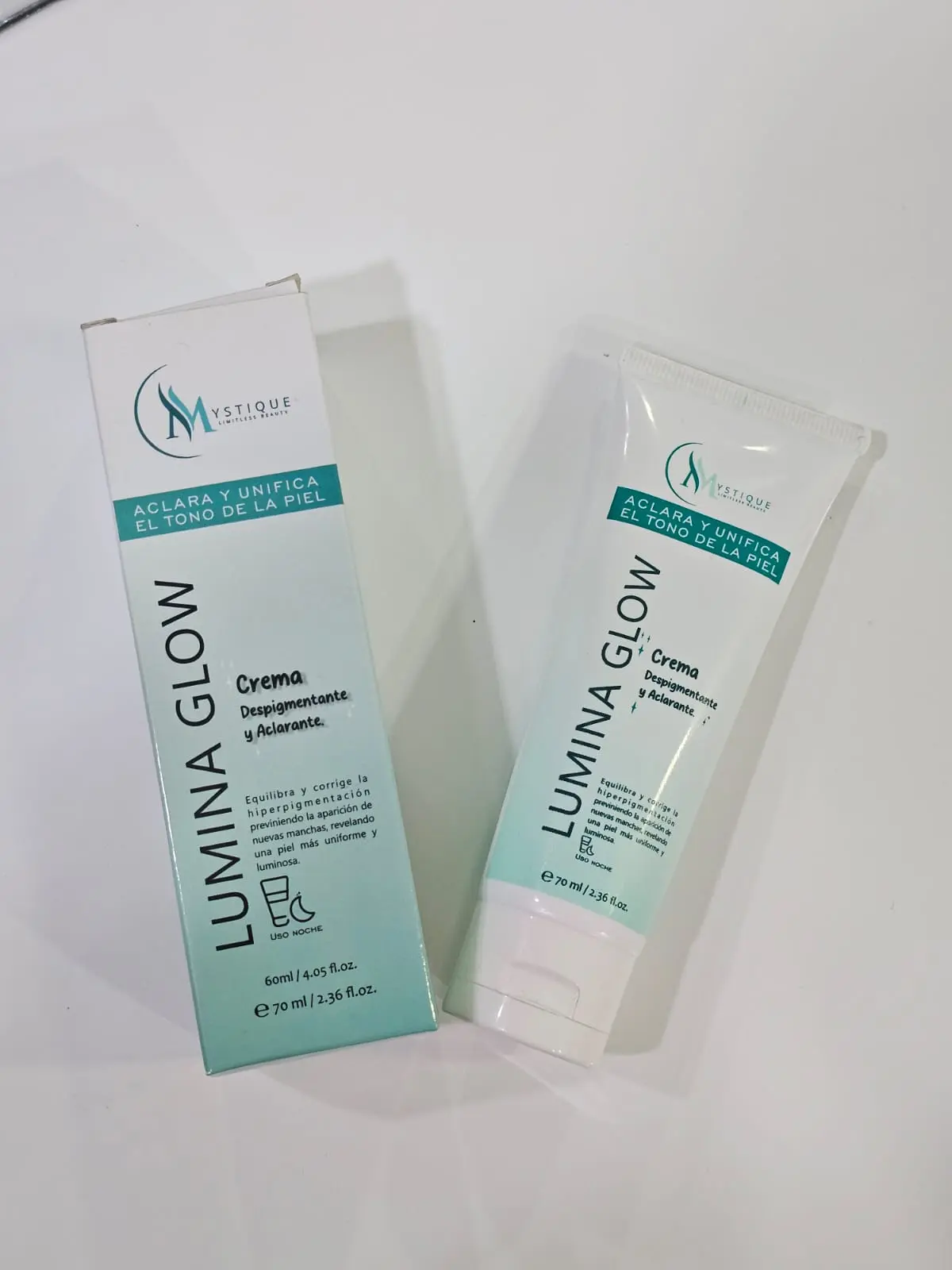 Crema despigmentante Lumina Glow de 70 ml junto a su caja, en envase blanco con detalles azul turquesa, diseñada para aclarar y unificar el tono de piel.