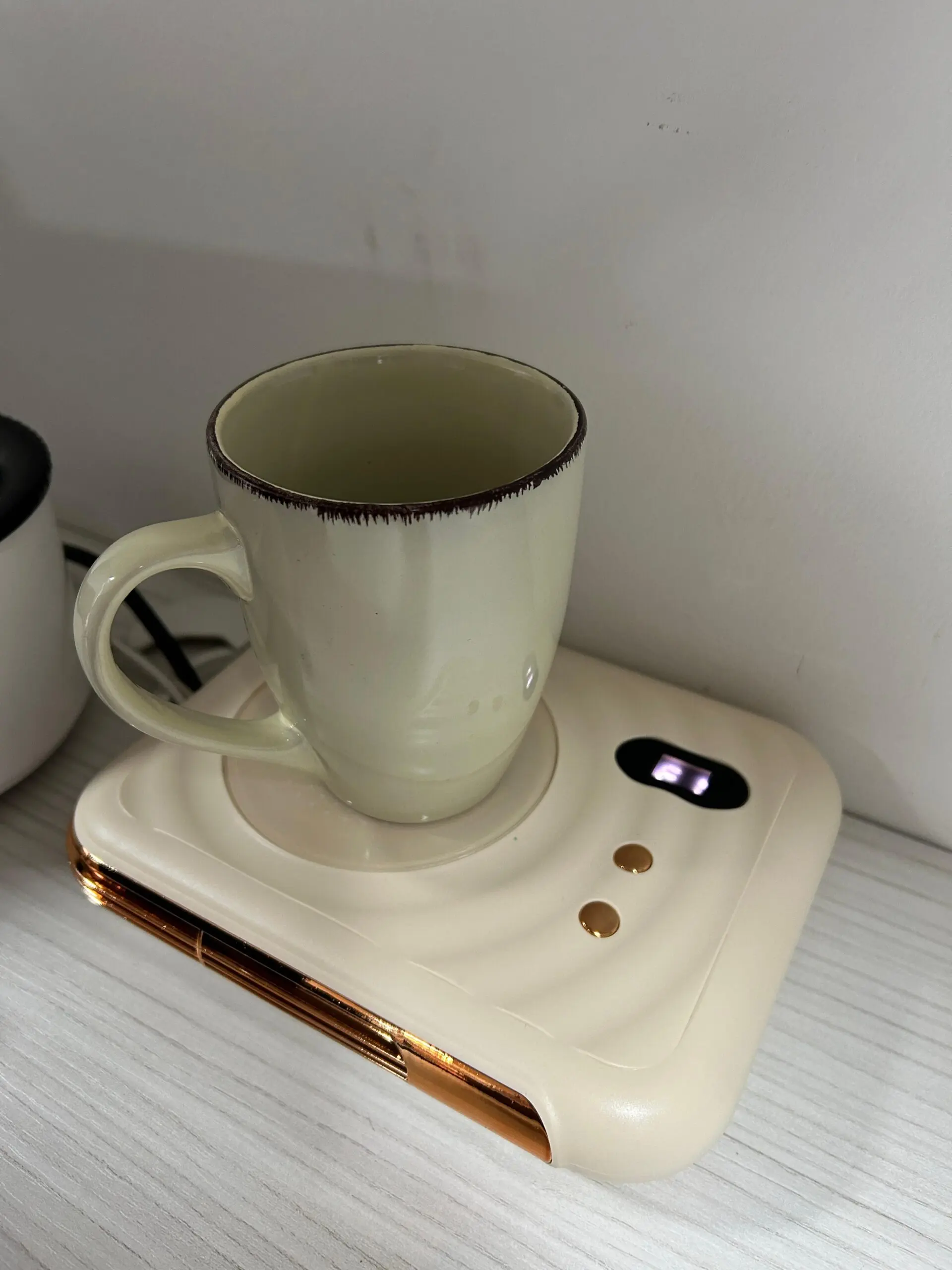 Calentador de tazas eléctrico beige con borde dorado, taza de cerámica y calefactor de aire.