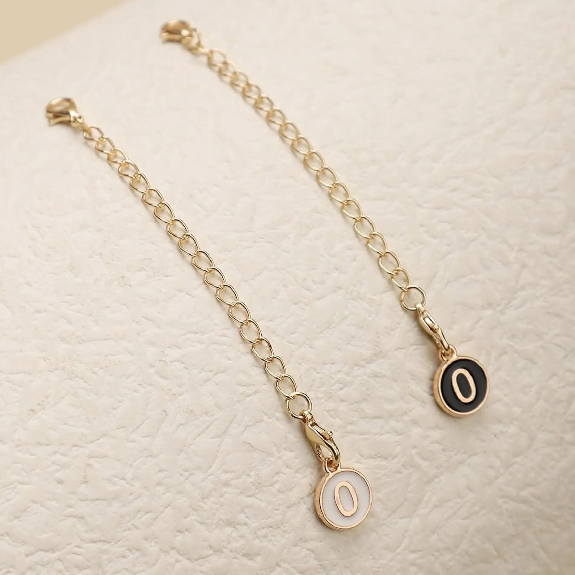 Extensores dorados con dije de número "0" blanco y negro para accesorios Stanley.