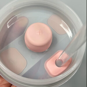 Kit antiderrame Stanley con tapa rosada y sorbete transparente en recipiente con agua.