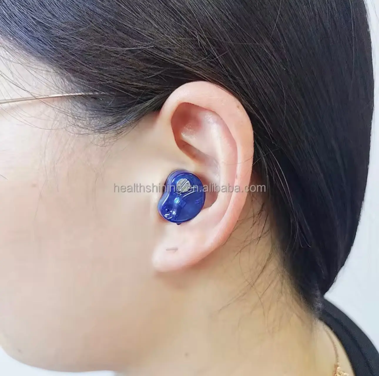 Amplificador de sonido azul translúcido para pérdida auditiva, ajustado en oído femenino con cabello oscuro.