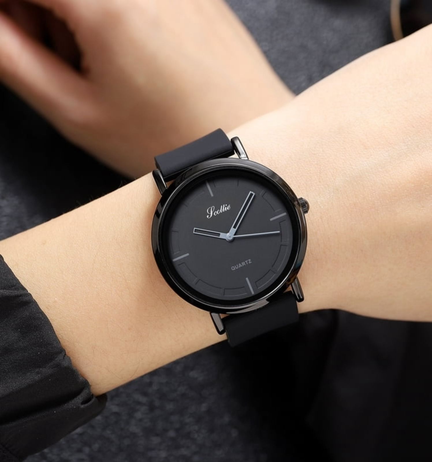 Reloj Scottie negro minimalista en muñeca, correa de silicona, esfera gris, resistente al agua.