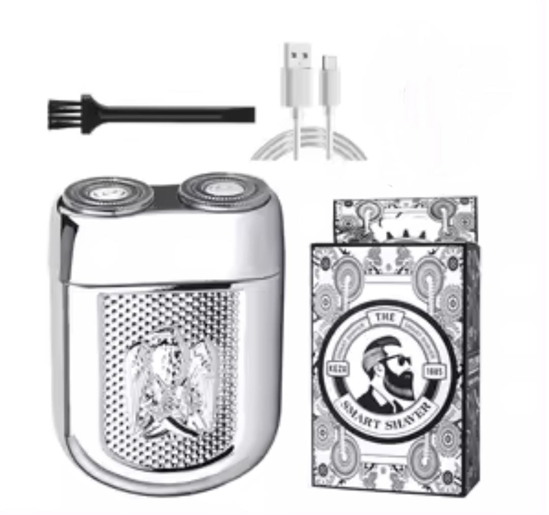 Mini afeitadora eléctrica plateada con dos cabezales, cepillo y cable USB-C, junto a su caja con diseño vintage.
