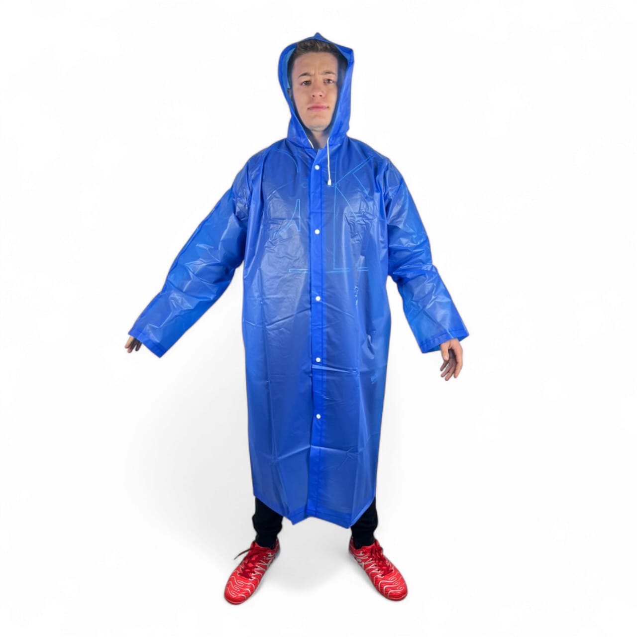 Hombre joven con capa impermeable azul brillante, con capucha, botones al frente y zapatillas rojas.