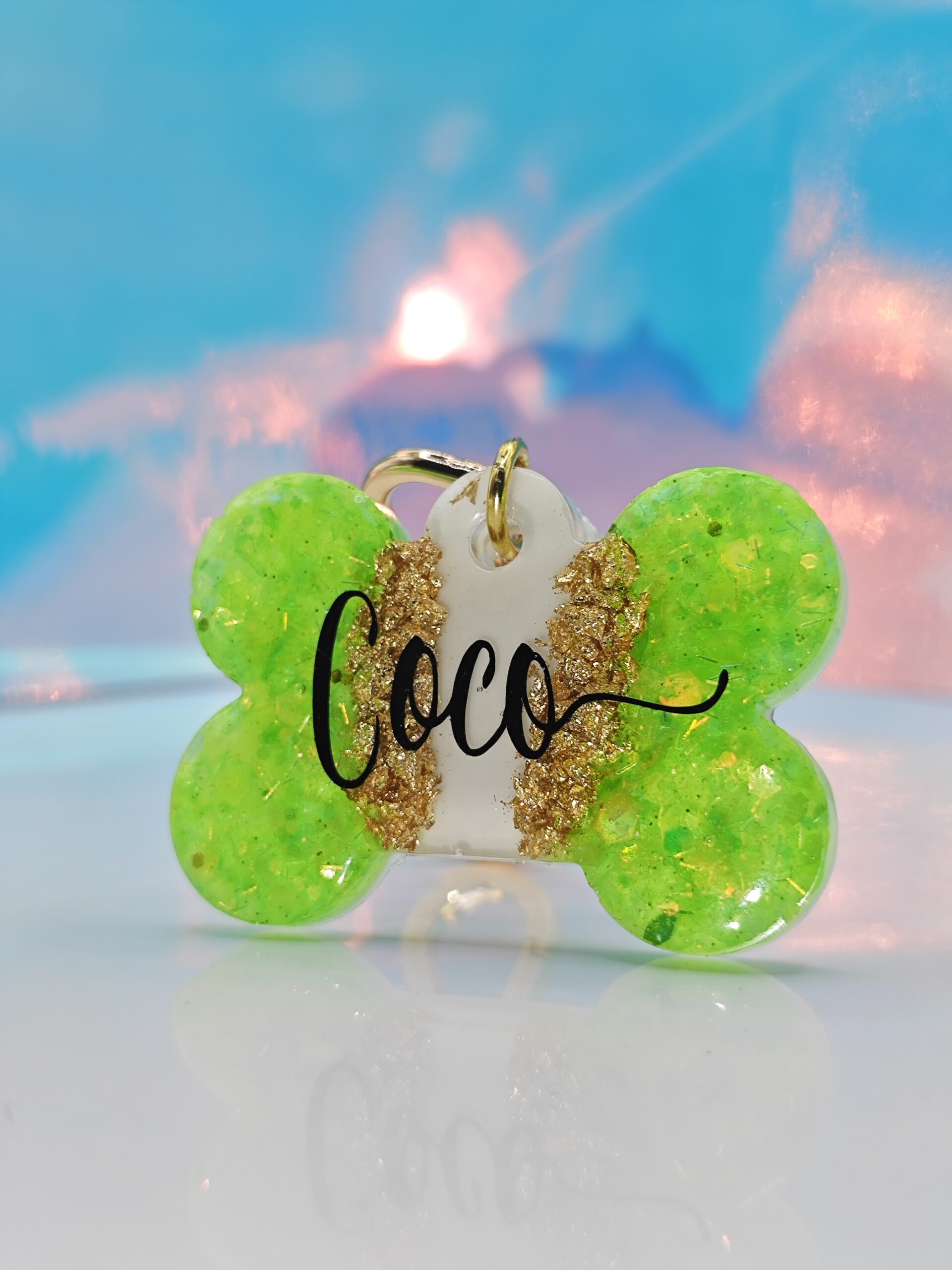 Placa hueso verde con nombre "Coco" en negro, detalles dorados, para collar de mascota.