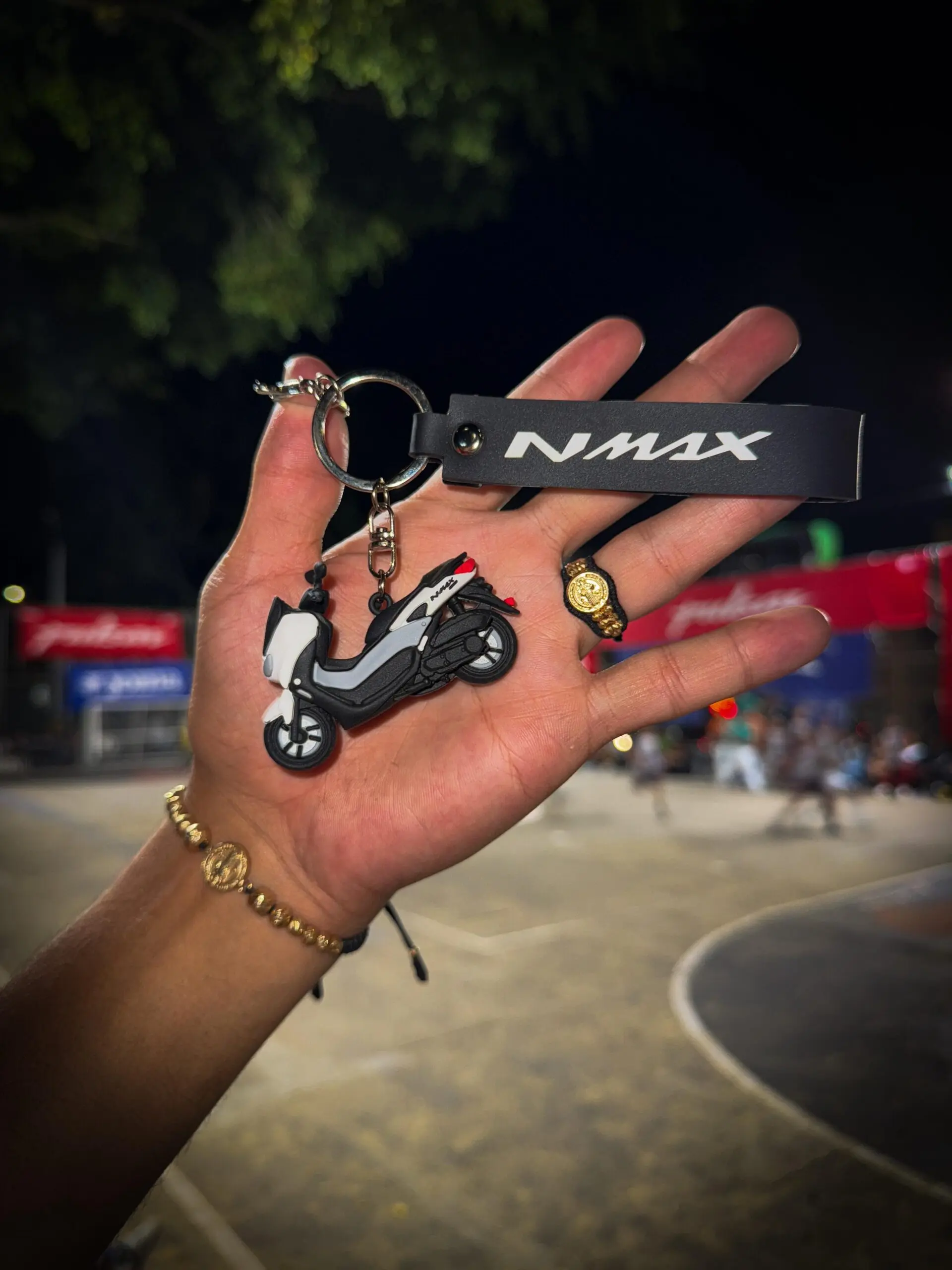 Llavero 3D moto NMAX gris con blanco y accesorio de corona dorada en mano.
