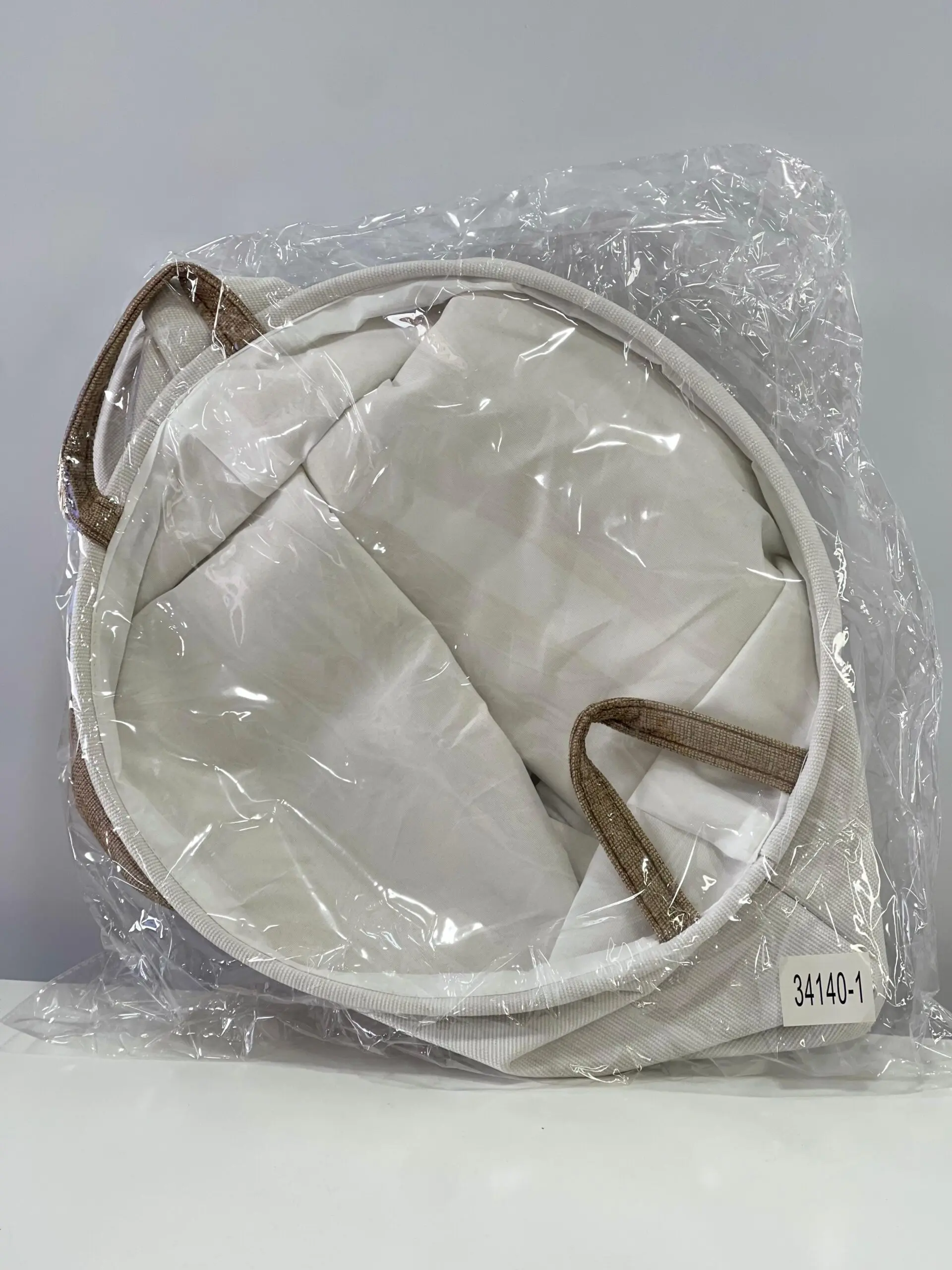 Cesto de ropa sucia de tela gris y blanco, con asas, en empaque plástico. Etiqueta "34140-1".