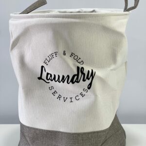 Cesto de tela para ropa sucia, blanco con base gris, diseño minimalista con texto "Laundry Services".