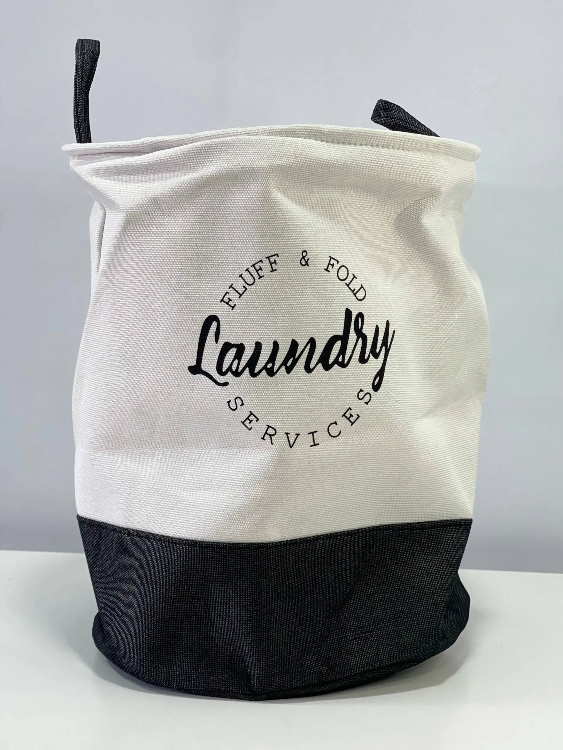 Cesto de tela para ropa sucia, blanco y gris, con texto "Laundry Services", ideal para organizar el hogar.