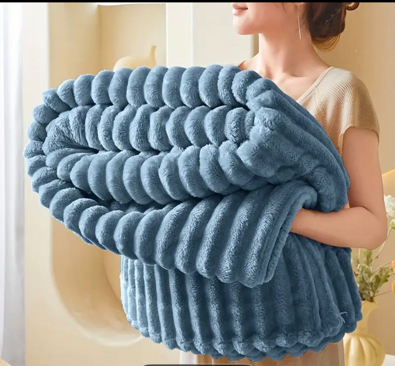Manta polar felpa de conejo azul con textura acanalada, sostenida por una mujer.
