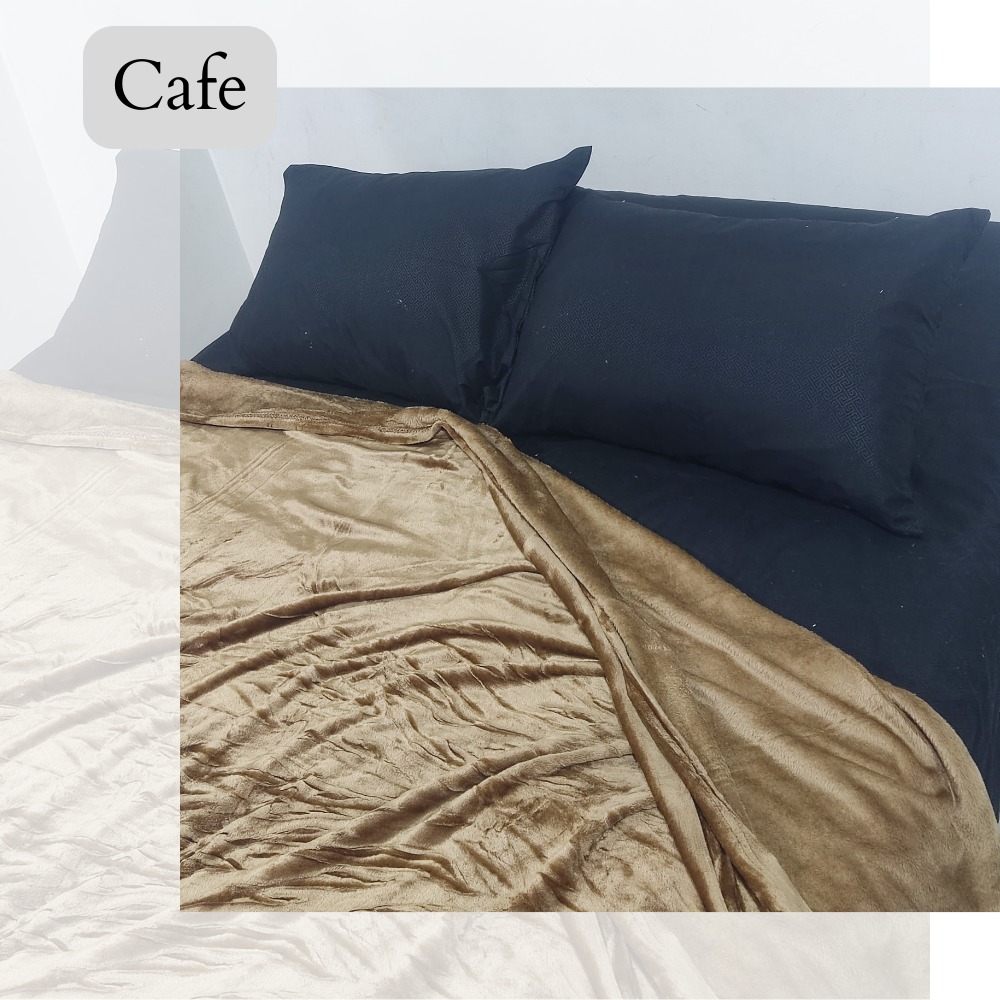 Cobija piel de durazno color café, textura suave, sobre cama con almohadas negras.